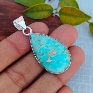 Könnte beinhalten: Ein tropfenförmiger Türkis-Anhänger mit silbernen Akzenten. Der Anhänger ist in einer Sterling-Silber-Öse gefasst.