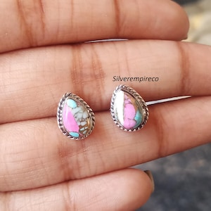 May include: A pair of teardrop-shaped stud earrings. Each earring features a vibrant mix of pink, turquoise, and brown stones, set within a silver-toned, rope-textured frame. The earrings are displayed on a neutral background.