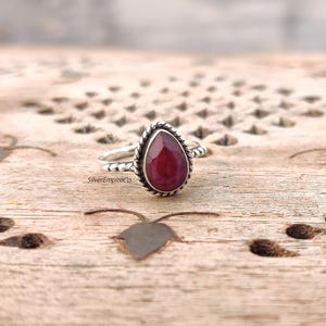 Puede incluir: Un anillo de rubí en forma de lágrima engastado en plata de ley. El anillo tiene una banda trenzada y un engaste de bisel.