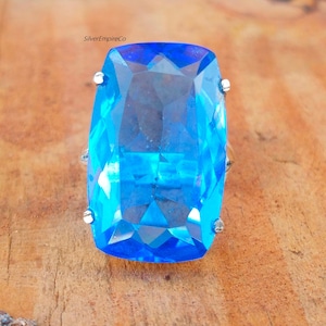 May include: A large, rectangular, blue gemstone ring with a silver setting.