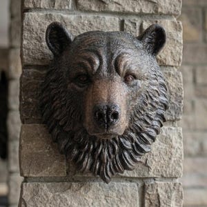 May include: A detailed, brown bear head sculpture mounted on a stone brick column. The bear has a realistic appearance with textured fur and a focused gaze. The sculpture is a decorative item.