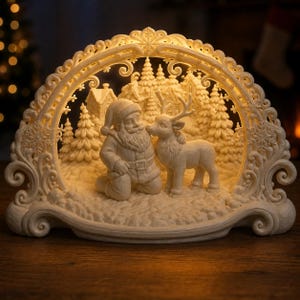 Könnte beinhalten: Ein beleuchteter, cremefarbener dekorativer Bogen mit einer skulpturalen Szene, die den Weihnachtsmann kniend neben einem Rentier zeigt. Der Hintergrund zeigt ein detailliertes Winterdorf mit Tannen und Häusern, eingerahmt von einer verzierten Bordüre.