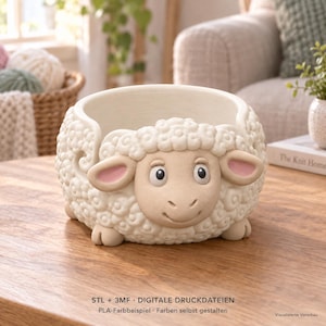 May include: A cream-coloured yarn bowl shaped like a sheep with a textured wool pattern, pink-tinted ears, and a smooth face. The bowl features a spiral cutout on the side for yarn feeding. Text at the bottom reads: STL + 3MF DIGITALE DRUCKDATEIEN.