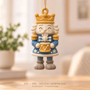 Könnte beinhalten: Ein hängendes Nussknacker-Ornament mit gelber Krone, weißem Haar und Bart sowie einer blauen Uniform mit gelben Akzenten. Die Figur hält eine gelbe Trommel und trägt einen blauen Mantel mit weißen Sternen. Text: STL + 3MF DIGITAL DOWNLOAD. Farbbeispiel.