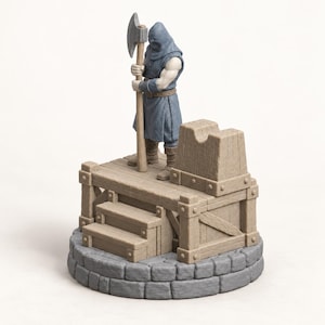 May include: A miniature figurine of a hooded executioner in a blue tunic holding a large axe, standing on a wooden platform with stairs and a block, all set upon a circular gray stone base. The figure has pale skin and wears brown boots.
