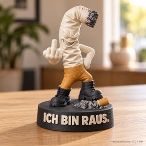 Könnte beinhalten: Eine Figur in Form einer Zigarette mit geknicktem Ende, grimmigem Gesicht und Armen, bekleidet mit schwarzen Stiefeln und orangefarbener Hose. Die Figur zeigt den Mittelfinger und steht auf einem schwarzen Sockel mit dem Text ICH BIN RAUS.
