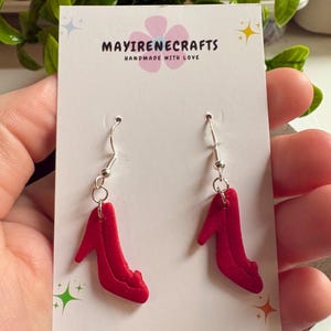 Puede incluir: Un par de pendientes rojos con forma de tacones altos, con ganchos plateados. Se exhiben en una tarjeta blanca con el texto "MAYIRENECRAFTS HANDMADE WITH LOVE".