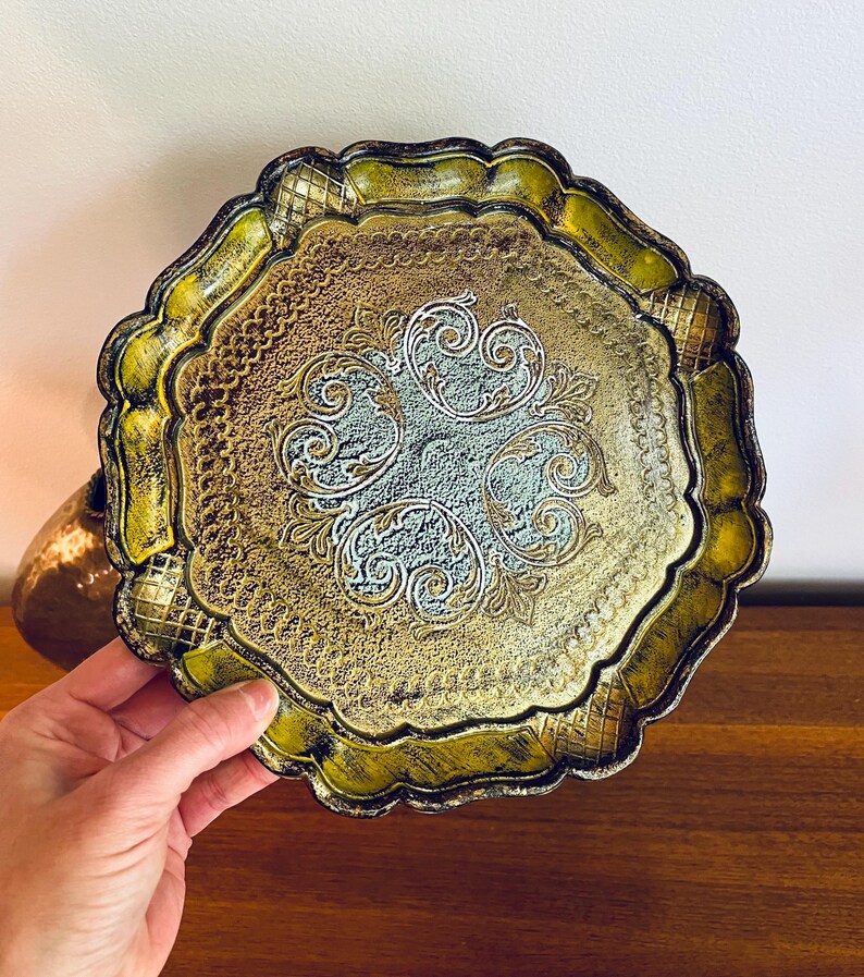 Pu&ograve; includere: Un vassoio decorativo dorato e verde con un bordo a festoni e un design intricato al centro. Il design &egrave; di colore blu chiaro e bianco.