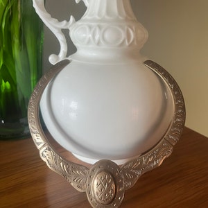 May include: A gold-toned metal necklace with an ornate design. The necklace features a large oval pendant with a geometric pattern.