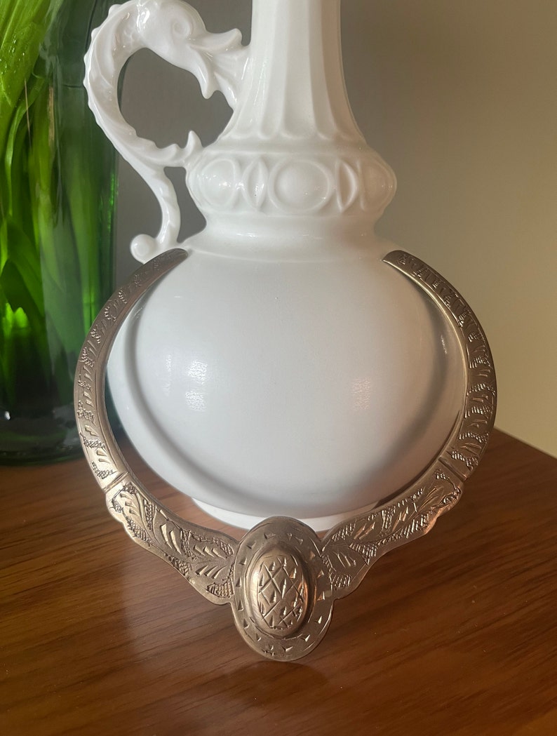 May include: A gold-toned metal necklace with an ornate design. The necklace features a large oval pendant with a geometric pattern.