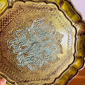 Pu&ograve; includere: Un vassoio decorativo dorato e verde con un bordo a festoni e un intricato disegno floreale.