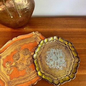 Pu&ograve; includere: Due vassoi decorativi con disegni ornamentali in oro e argento. Il vassoio pi&ugrave; grande &egrave; arancione con accenti dorati, e il vassoio pi&ugrave; piccolo &egrave; dorato con accenti argentati.
