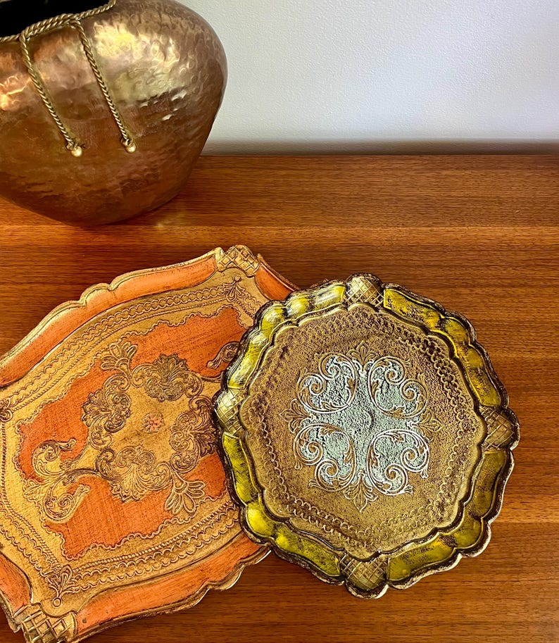 Pu&ograve; includere: Due vassoi decorativi con disegni ornamentali in oro e argento. Il vassoio pi&ugrave; grande &egrave; arancione con accenti dorati, e il vassoio pi&ugrave; piccolo &egrave; dorato con accenti argentati.