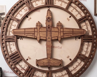 May include: A wooden wall art piece featuring a detailed airplane design at the center, surrounded by a compass rose. The outer ring displays degree markings and directional indicators. The piece is made of light and dark brown wood.