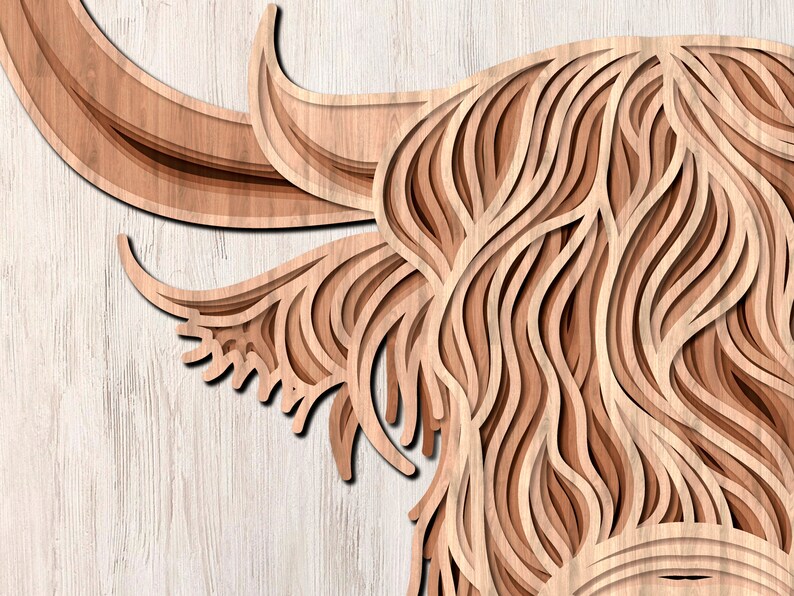 May include: A close-up of a wooden cutout of a Highland cow's head. The cow's fur is depicted with intricate layered lines, creating a 3D effect. The wood is a light brown color.