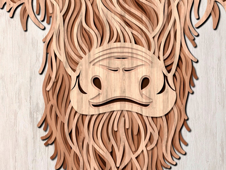 May include: Close-up of a wooden cutout of a Highland cow's face. The cow's fur is made of layered wood, creating a 3D effect. The cow's nose and eyes are visible.