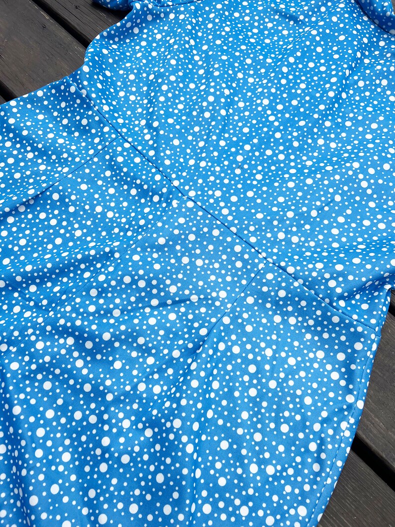 Puede incluir: Un vestido azul con estampado de lunares blancos. El vestido tiene un corpi&ntilde;o ajustado y una falda fluida.
