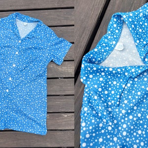 Puede incluir: Un vestido de manga corta azul y blanco con lunares, cuello y cierre de botones.
