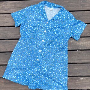 Puede incluir: Un vestido azul y blanco de lunares con botones y manga corta.