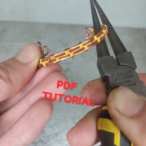 May include: A close-up of a copper wire jewelry piece being crafted with pliers. The piece is a bar shape with intricate woven wire detailing. The text "PDF TUTORIAL" is superimposed in red.