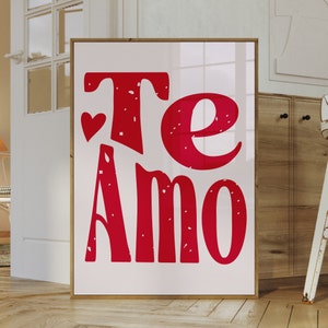 Könnte beinhalten: Ein weißer gerahmter Druck mit den Worten "Te Amo" in Rot mit einem kleinen roten Herzen über dem "Te".