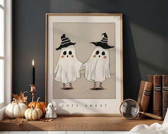 May include: A framed wall art print featuring two white ghosts wearing black and white striped witch hats and matching striped socks. The ghosts have round black eyes and pink cheeks. The text CUTE GHOST is printed in black at the bottom of the illustration.