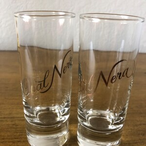 May include: Two clear glass shot glasses with a gold inscription that reads "Gal Nero".