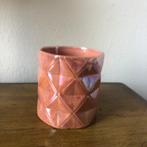 May include: A small, terracotta-colored ceramic planter with a geometric diamond pattern. The planter has a glossy finish and iridescent highlights.