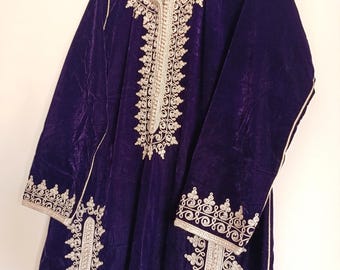 May include: A long, dark purple velvet garment with intricate gold embroidery along the neckline, down the front, and on the sleeves. The embroidery features ornate floral and scrollwork patterns. The garment is hanging on a blue hanger.