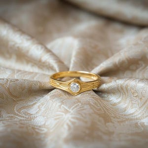 The design is cast in 14k Yellow Gold with a deep red Garnet center. The transformation shifts the aesthetic from "Silver Ranger" to "Royal Guard." The gold amplifies the warmth of the design, making it look like a piece of ancient ceremonial jewelry. The red stone adds a touch of danger and passion, perfect for a romantic, "Power Couple" anniversary gift.