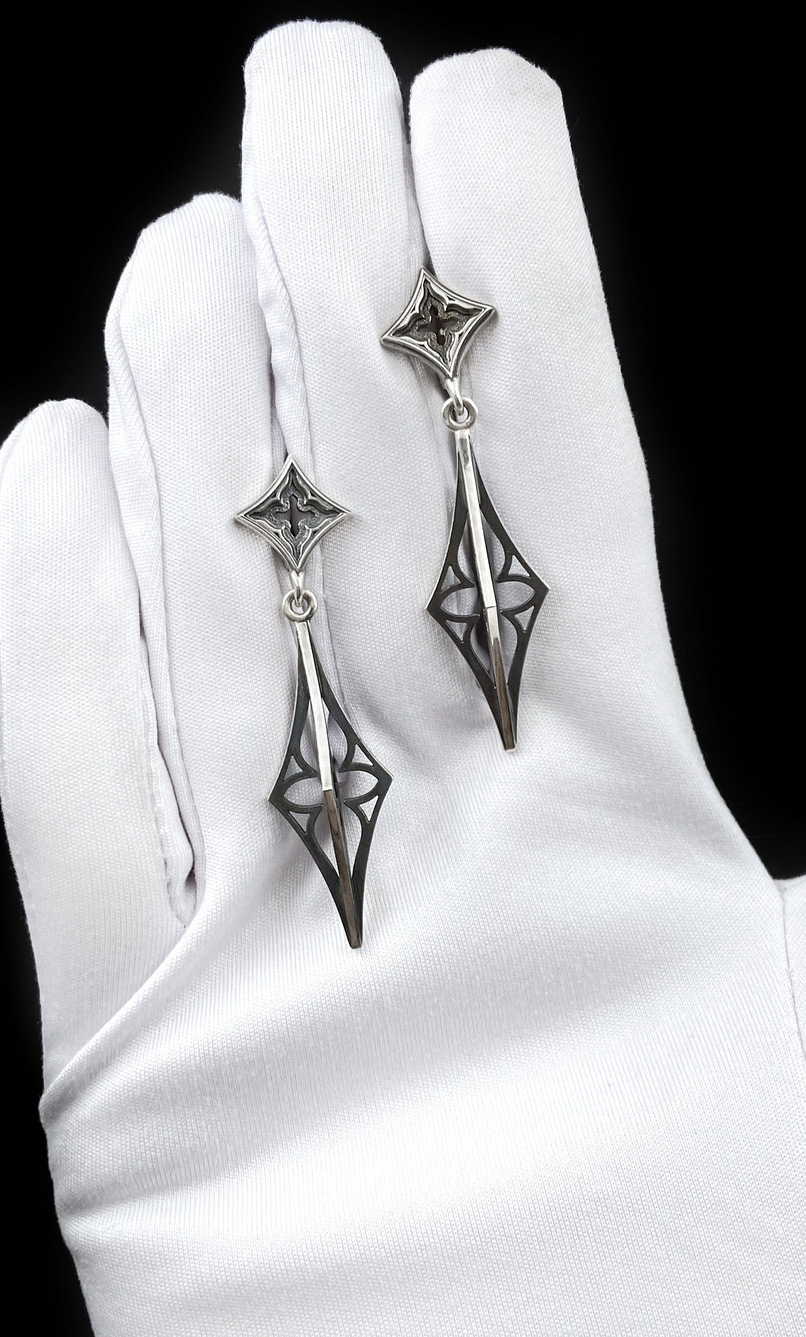 Sterling silver gothic earrings displayed on white gloves with intricate cathedral-style cutouts