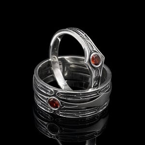 The image showcases the structural balance of the ring. The "tiara" dip in the center allows it to stack perfectly with a chevron or curved wedding band. The engraving is sharp and precise, demonstrating modern CNC or expert hand-carving techniques. The beveling on the edges gives the ring a "blade-like" sharpness visually, while remaining smooth to the touch.