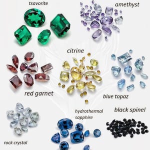 May include: An assortment of gemstones, including tsavorite, amethyst, citrine, red garnet, blue topaz, rock crystal, hydrothermal sapphire, and black spinel. The gemstones are in various shapes and sizes, with a range of colors from green to purple, yellow, red, blue, and black.