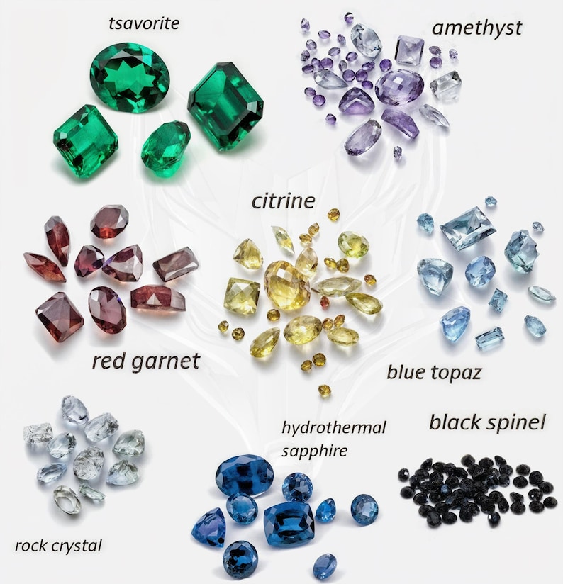 May include: An assortment of gemstones, including tsavorite, amethyst, citrine, red garnet, blue topaz, rock crystal, hydrothermal sapphire, and black spinel. The gemstones are in various shapes and sizes, with a range of colors from green to purple, yellow, red, blue, and black.