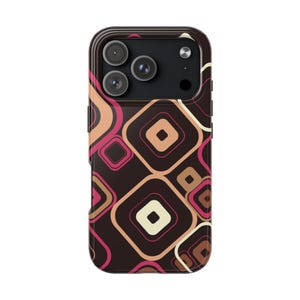 May include: A smartphone case featuring a dark brown background with a repeating pattern of overlapping squares in shades of cream, peach, and magenta. The case has a black camera module cutout at the top with three circular lenses and a flash.