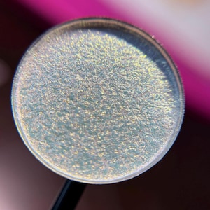 May include: A round, silver-rimmed container filled with a light blue, iridescent, glittery substance.