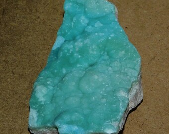 May include: A large, irregularly shaped piece of turquoise blue mineral with a white, crystalline texture. The mineral has a smooth, polished surface and a light blue color.