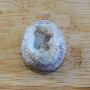 May include: A geode with a hollow interior filled with white crystals. The geode is a light brown color with a rough texture.