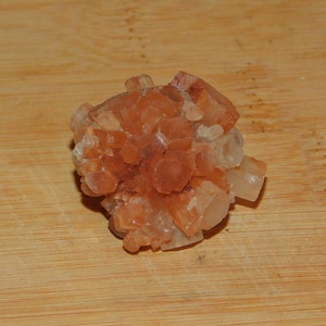 May include: A cluster of orange and white calcite crystals in a starburst shape.