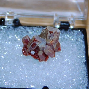 Puede incluir: Un grupo de cristales rojos y grises en una caja de espuma blanca.