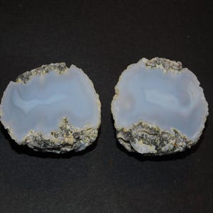 May include: Two halves of a geode with a light blue, translucent interior and a rough, gray exterior.