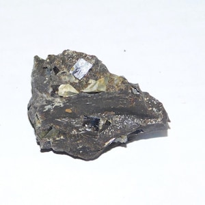 May include: A dark gray rock with several small, shiny, black crystals embedded in it.
