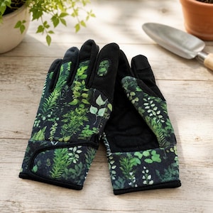 May include: A pair of gardening gloves featuring a dark black base with a vibrant green botanical print of various fern and leaf patterns. The gloves have solid black fabric on the palms and fingertips, with adjustable wrist straps and reinforced sections.