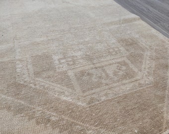 May include: A beige rug with a faded, intricate pattern. The rug has a subtle, textured weave.