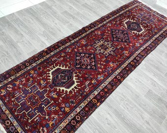 Op de afbeelding: Een rood, blauw en crèmekleurig Perzisch tapijt met een traditioneel geometrisch patroon. Het tapijt heeft aan beide uiteinden franjes.