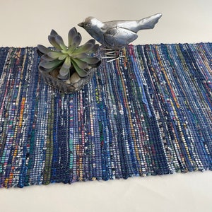 May include: A blue and white woven rug with a small succulent plant in a pot and a silver bird figurine on top.