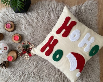 May include: A white throw pillow with the word "HOHO" embroidered in red and white yarn. The pillow is on a fluffy white rug.