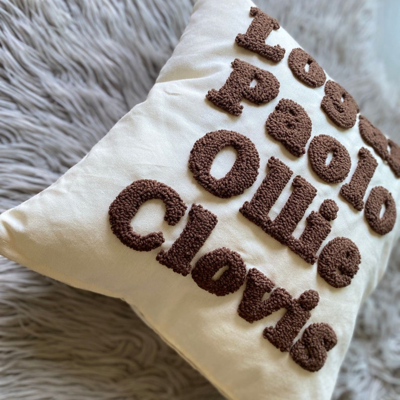 May include: White pillow with brown embroidered letters that spell "I love Paolo Ollie Clovis".