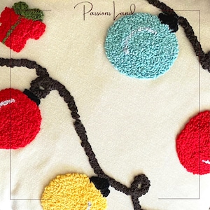 Puede incluir: Una almohada blanca con una cadena de luces marrones, adornos circulares rojos, amarillos y azules, y el texto "Passions Land".