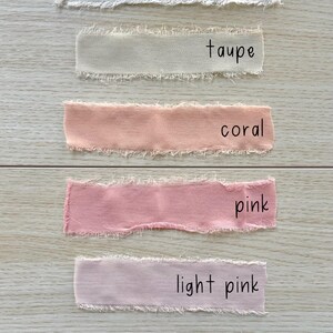 Pu&ograve; includere: Sei strisce di nastro in tessuto con bordi sfilacciati disposte orizzontalmente. I colori sono etichettati come vanilla, taupe, coral, pink, light pink e ivory. Ogni striscia presenta un aspetto morbido e strutturato con fili sciolti visibili.